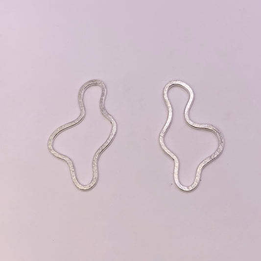 Product foto op witte achtergrond. Asymmetrische oorbellen met vrije vorm. Voor- en achterzijde gematteerd, binnen en buitenkant hoogglans