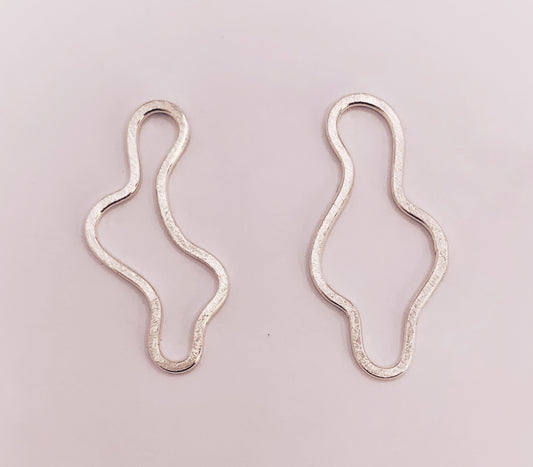 Product foto op witte achtergrond. Asymmetrische oorbellen met vrije vorm. Voor- en achterzijde gematteerd, binnen en buitenkant hoogglans