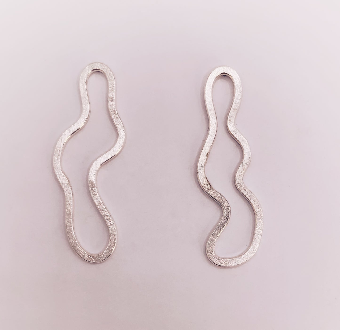 Product foto op witte achtergrond. Asymmetrische oorbellen met vrije vorm. Voor- en achterzijde gematteerd, binnen en buitenkant hoogglans