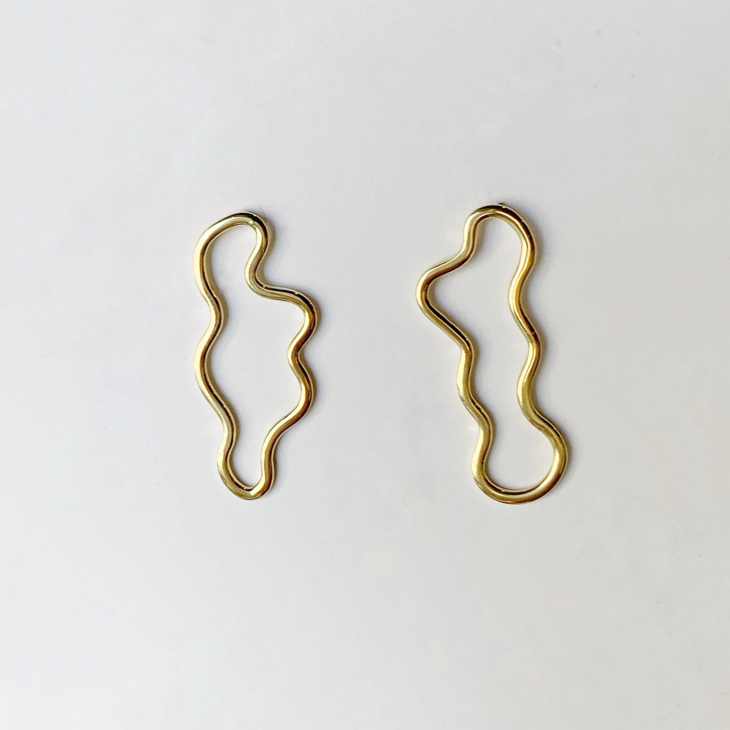 Productfoto op witte achtergrond van geelgouden oorbellen met vrije vorm
