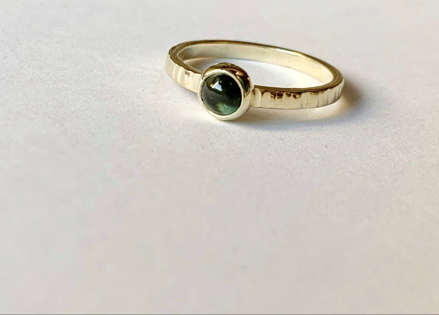 Productfoto op witte achtergrond van een geelgouden ring met cabochon geslepen groene toermalijn