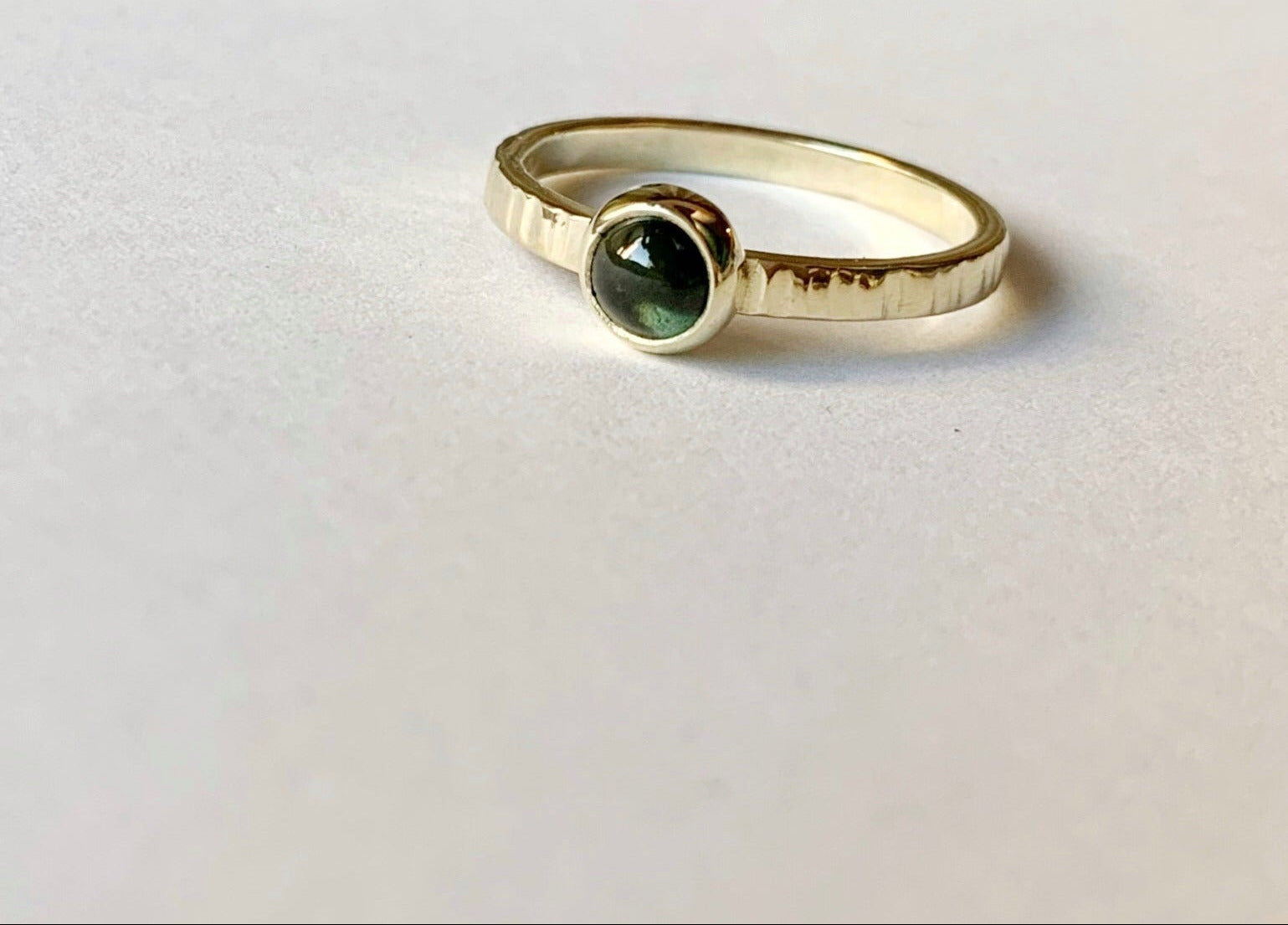 Productfoto op witte achtergrond van een geelgouden ring met cabochon geslepen groene toermalijn