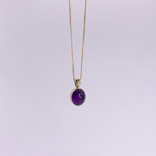 Productfoto op witte achtergrond, close-up van ovale, cabochon geslepen amethist hanger. Hangt aan een collier met gourmet schakel