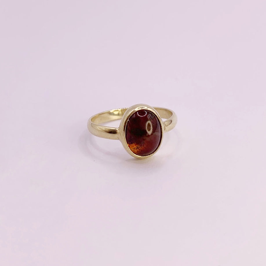 product foto op witte achtergrond van geelgouden ring met halfronde scheen en ovale, cabochon geslepen mosagaat