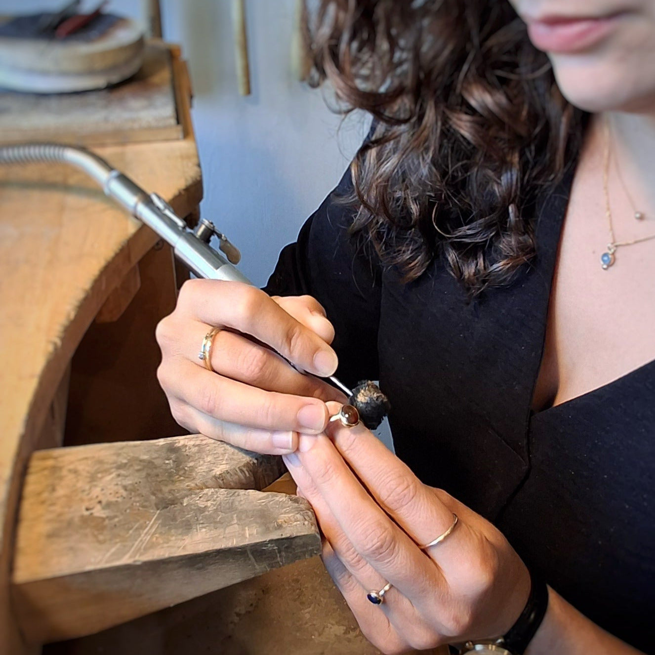 Close-up achter de werkbank, ingezoomd op handen die met de hangmoter een ring polijsten