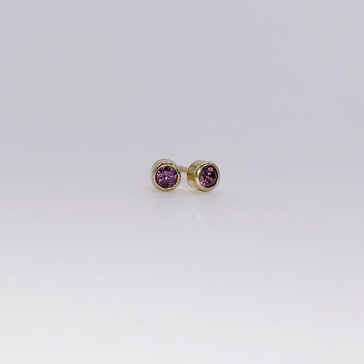 Productfoto op witte achtergrond, geelgouden oorknopjes met facet geslepen paarse granaat