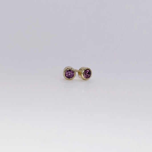 Productfoto op witte achtergrond, geelgouden oorknopjes met facet geslepen paarse granaat