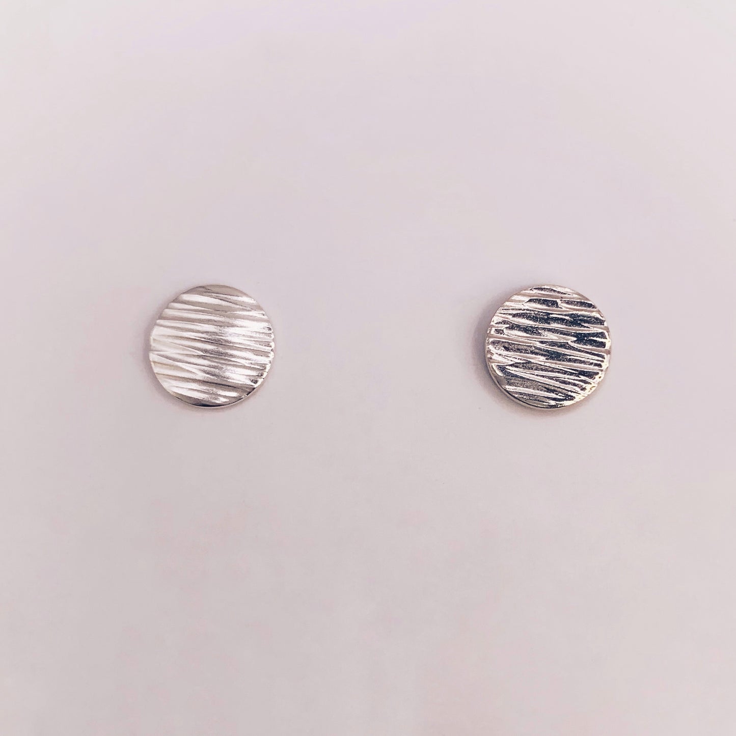 Productfoto op witte achtergrond. Oorstekertjes met hammerslag waardoor zij lijken op knoopjes