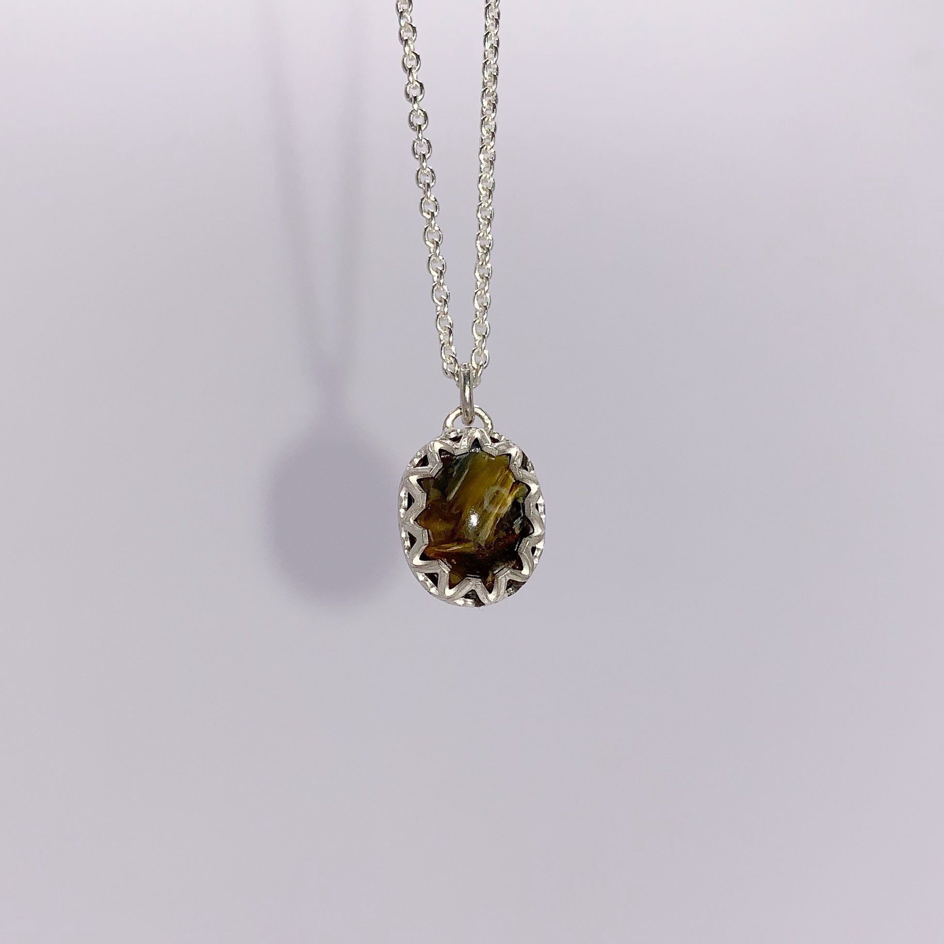 productfoto op witte achtergrond, close-up van pieterset hanger in fantasiezetting aan een anker collier. Collier en zetting zijn zilver