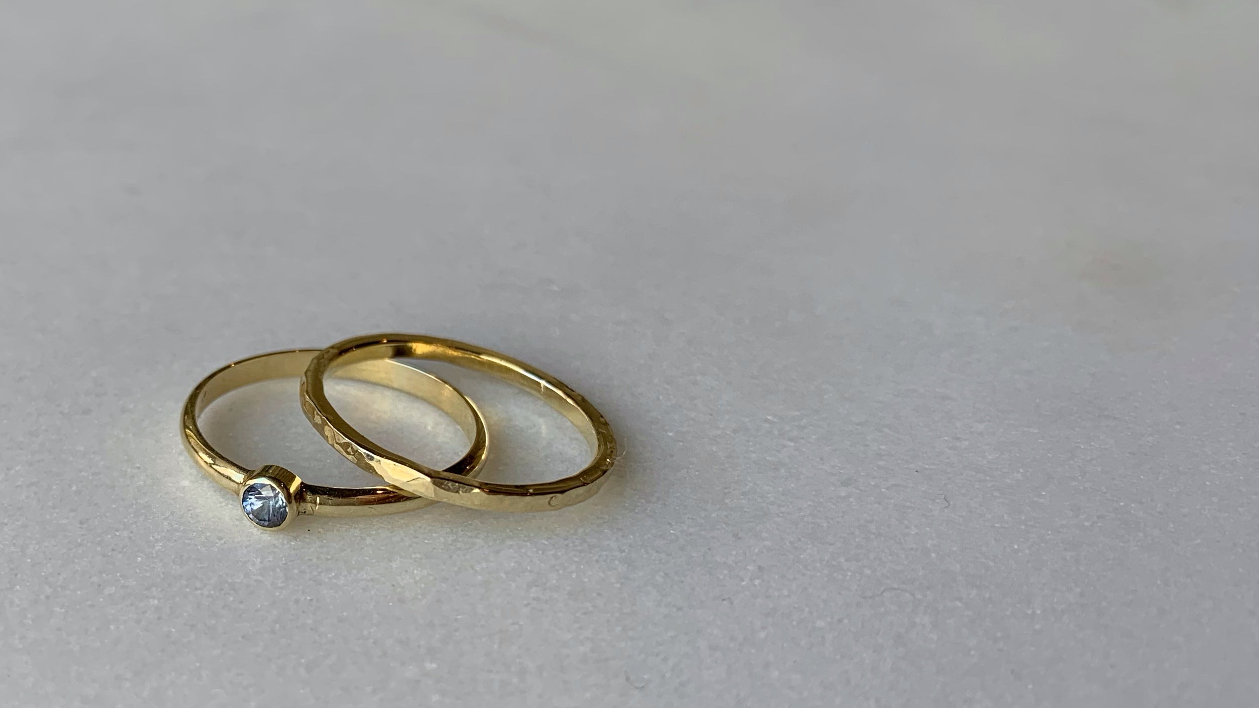 Twee geelgouden ringen, een met facet geslepen steen in gladomzetting en een met gehamerde bewerking